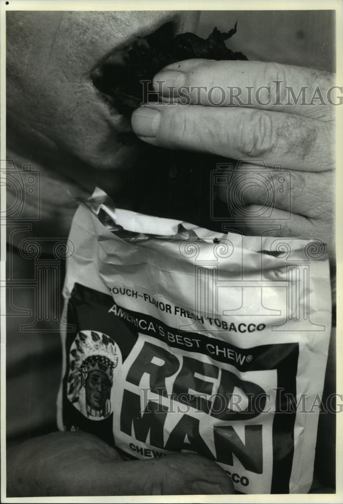 1989 Press Photo Man Puts Red Man Chewing Tobacco in Mouth - noa76148